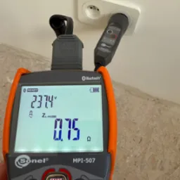 Miernik Sonel MPI-507 z podłączoną wtyczką do gniazdka elektrycznego, wyświetlający wartości pomiarowe napięcia 237.4V i impedancji pętli zwarcia 0.75 Ω.