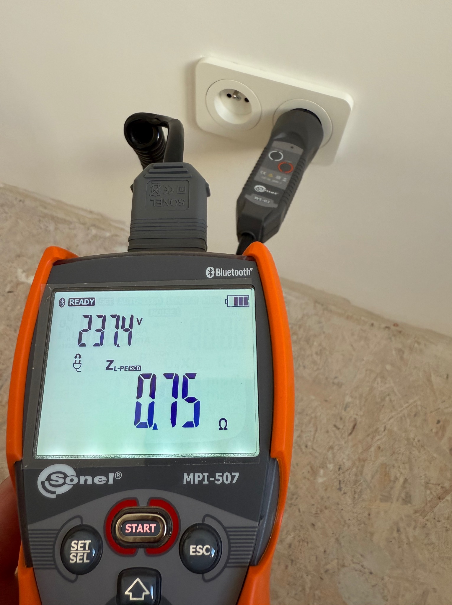 Miernik Sonel MPI-507 z podłączoną wtyczką do gniazdka elektrycznego, wyświetlający wartości pomiarowe napięcia 237.4V i impedancji pętli zwarcia 0.75 Ω.