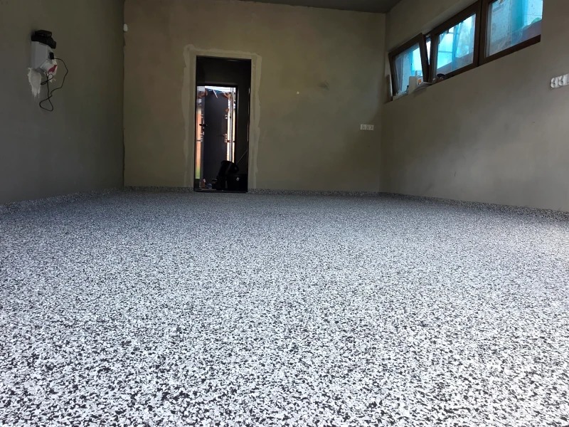 Wykończona posadzka żywiczna w pomieszczeniu z surowymi ścianami. Widoczne okno i drzwi. Biało-czarna, wzorzysta powierzchnia podłogi.