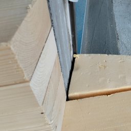 constructionmonter@gmail.com - Detale połączenia drewnianych elementów konstrukcyjnych, widoczne fragmenty płyty izolacyjnej i ściany.