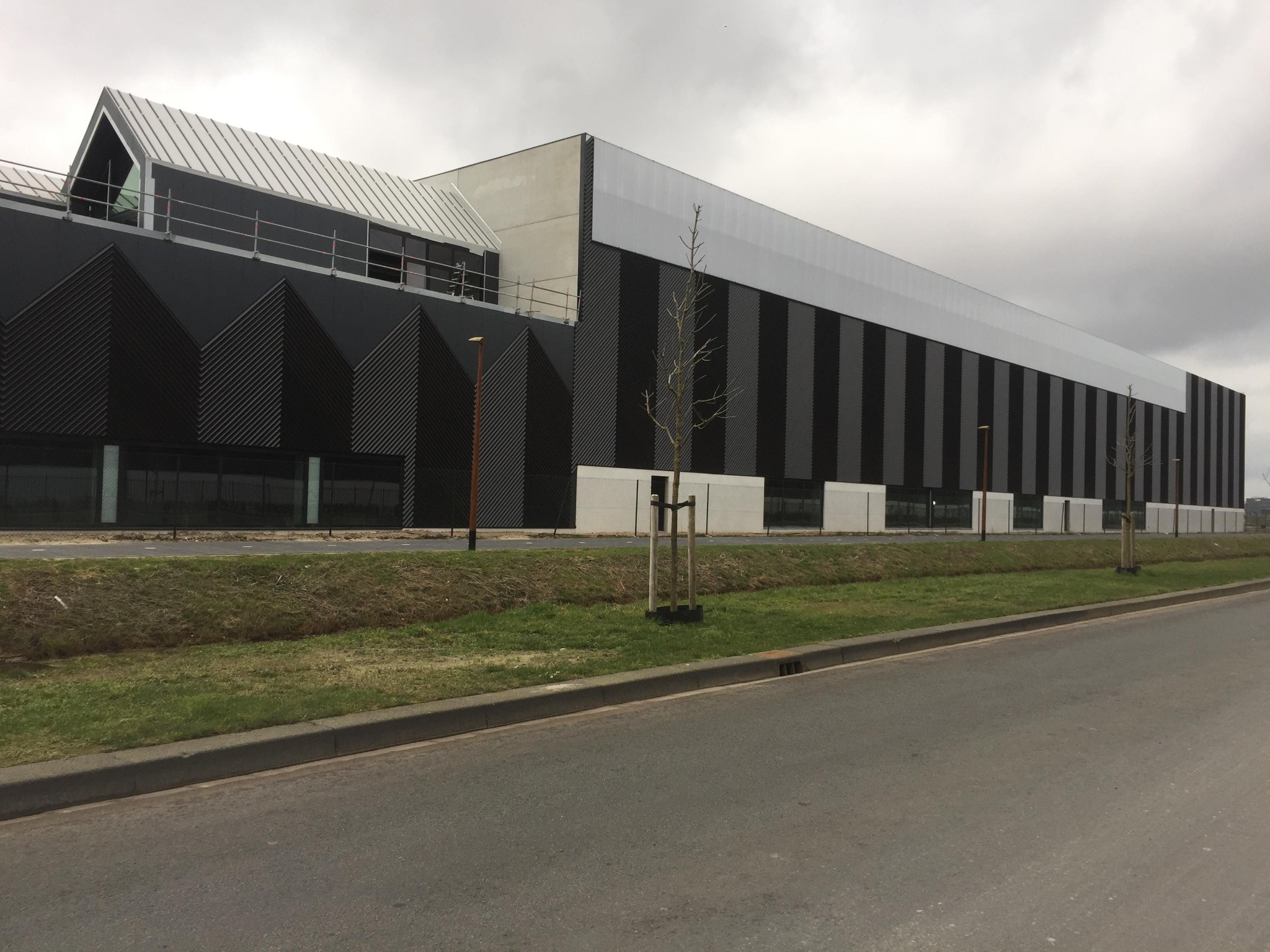 Nowoczesny budynek biurowy z czarno-białą elewacją, widok zewnętrzny w pochmurny dzień.