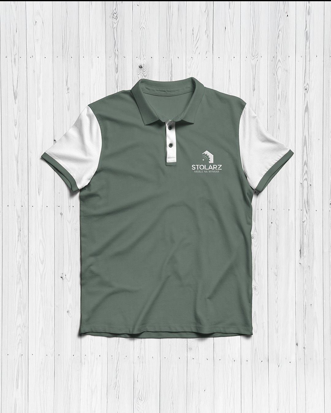 Zielona koszulka polo z białymi rękawami i logo 'Stolarz Meble na Wymiar' na tle białych drewnianych desek.
