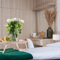 Ośrodek Wypoczynkowy Pod Dębem MARTA ŁUKAWSKA - Pokój hotelowy w Wójtowicach z łóżkiem, śniadaniem na tacy, bukietem białych róż w wazonie i elementami wyposażenia, takimi jak szafa, toaletka i lampka nocna.