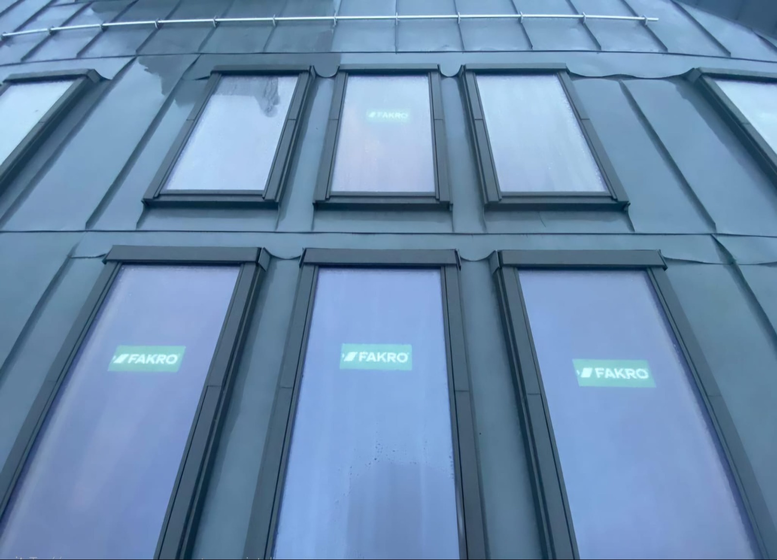 Metalowy dach z oknami dachowymi firmy Fakro, widok z dołu, szare wykończenie.