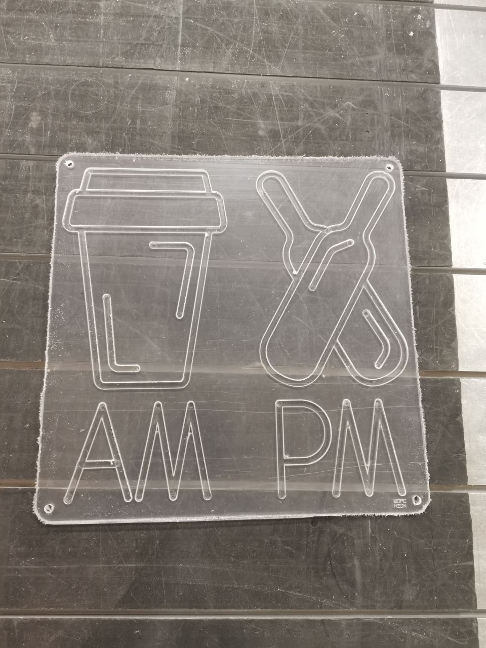 Płyta z pleksi z wygrawerowanym napisem 'AM PM' oraz symbolami kawy i drinków, wykonana metodą obróbki CNC w Wiktorowicach.