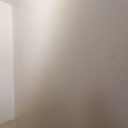 MATS-BUD - Świeżo pomalowane, jednolite ściany w rogu pomieszczenia, widoczne łączenie ścian i podłogi.