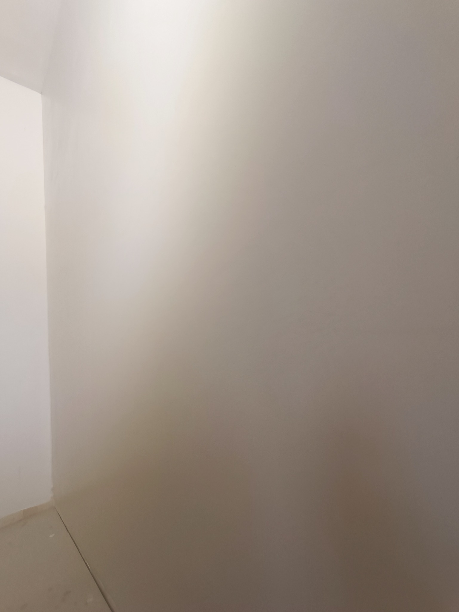 Świeżo pomalowane, jednolite ściany w rogu pomieszczenia, widoczne łączenie ścian i podłogi.