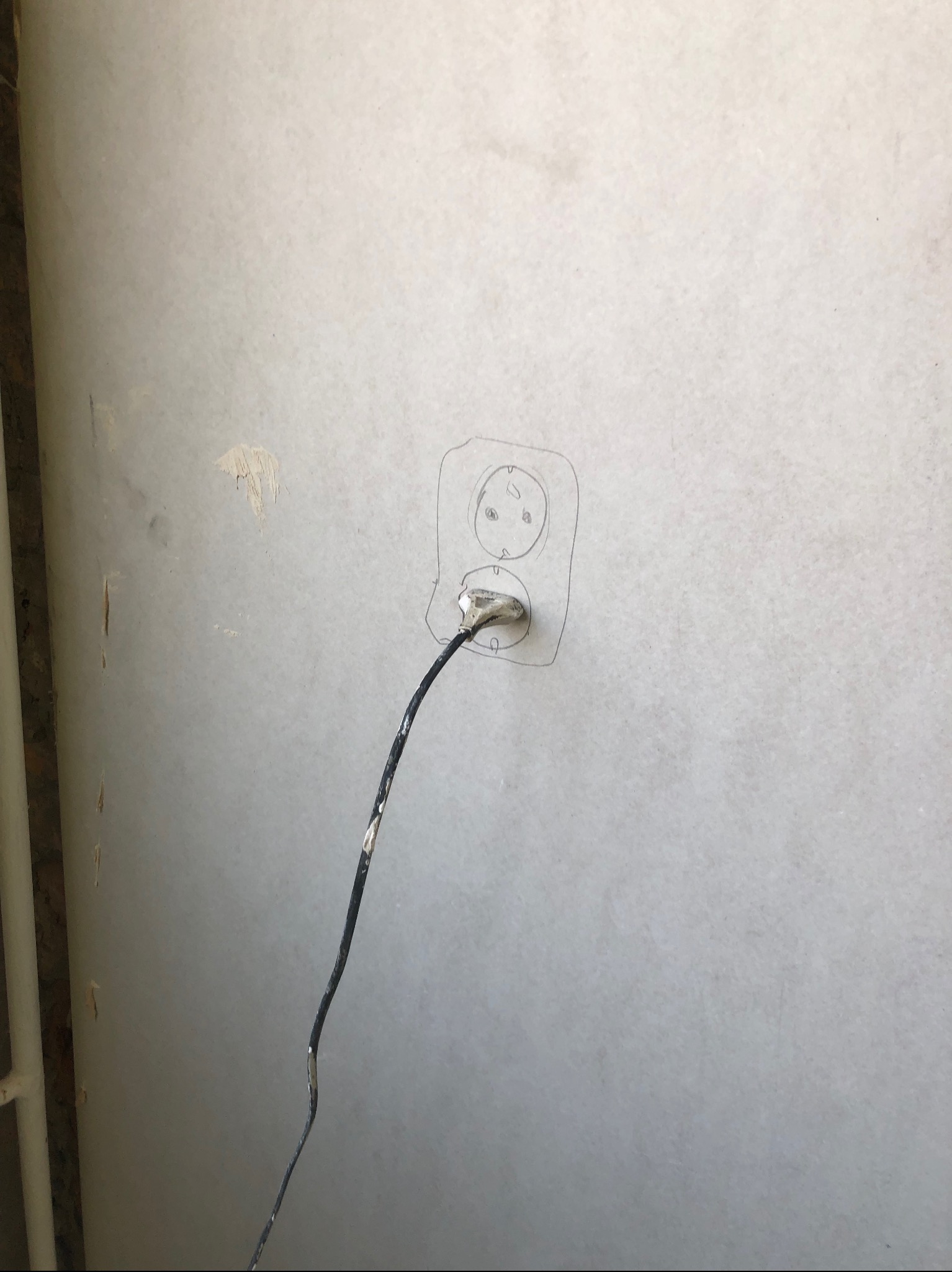 Szkic gniazdka elektrycznego na szarej ścianie z wystającym przewodem, widoczne ślady po usuniętej farbie.