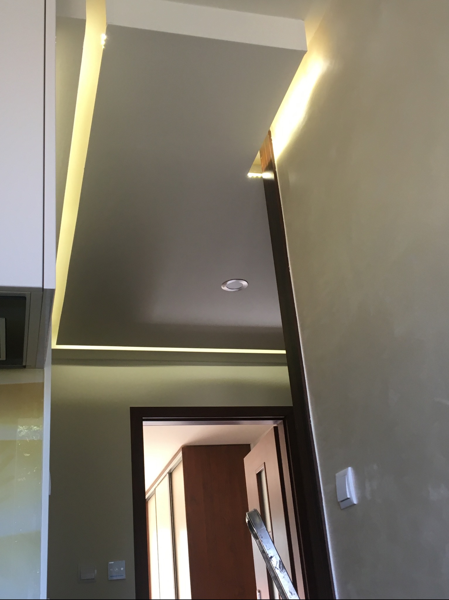 Oświetlenie LED w suficie podwieszanym, widok na korytarz z drzwiami, świeżo pomalowane ściany w neutralnym odcieniu.