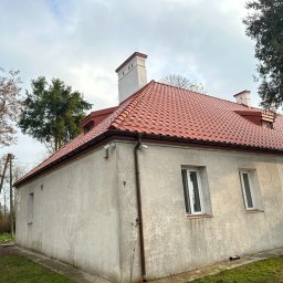 KS System KAMIL SZCZEPANIK - Budynek z nowym, czerwonym dachem ceramicznym, białymi kominami i rynnami, widok z zewnątrz w pochmurny dzień.