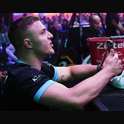 Patryk Buczkowski Gastrofazka - Mężczyzna w sportowej koszulce z tatuażem na ramieniu, nagrywający coś telefonem na tle widowni.