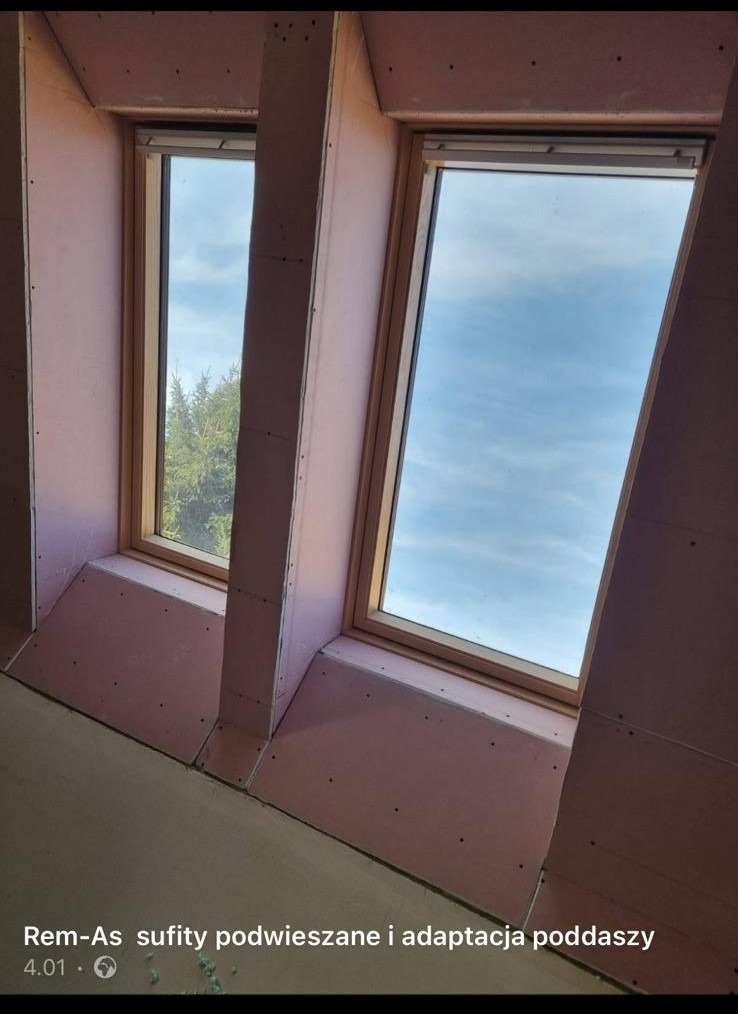 Montaż płyt gipsowo-kartonowych wokół okien dachowych na poddaszu w Resku, widoczne niezagruntowane płyty w kolorze różowym.