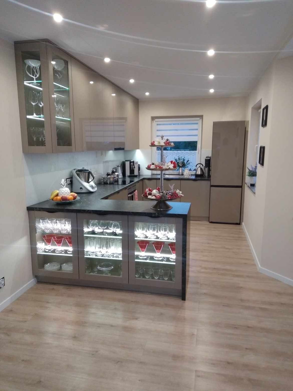 Nowoczesna kuchnia w Kartuzach z podświetlanymi szafkami i barkiem, eleganckie wykończenie, sprzęt AGD. Jasne, przestronne wnętrze.