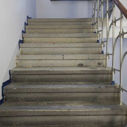 Schody z piaskowca częściowo wyczyszczone z brudu i powłok zabezpieczających.