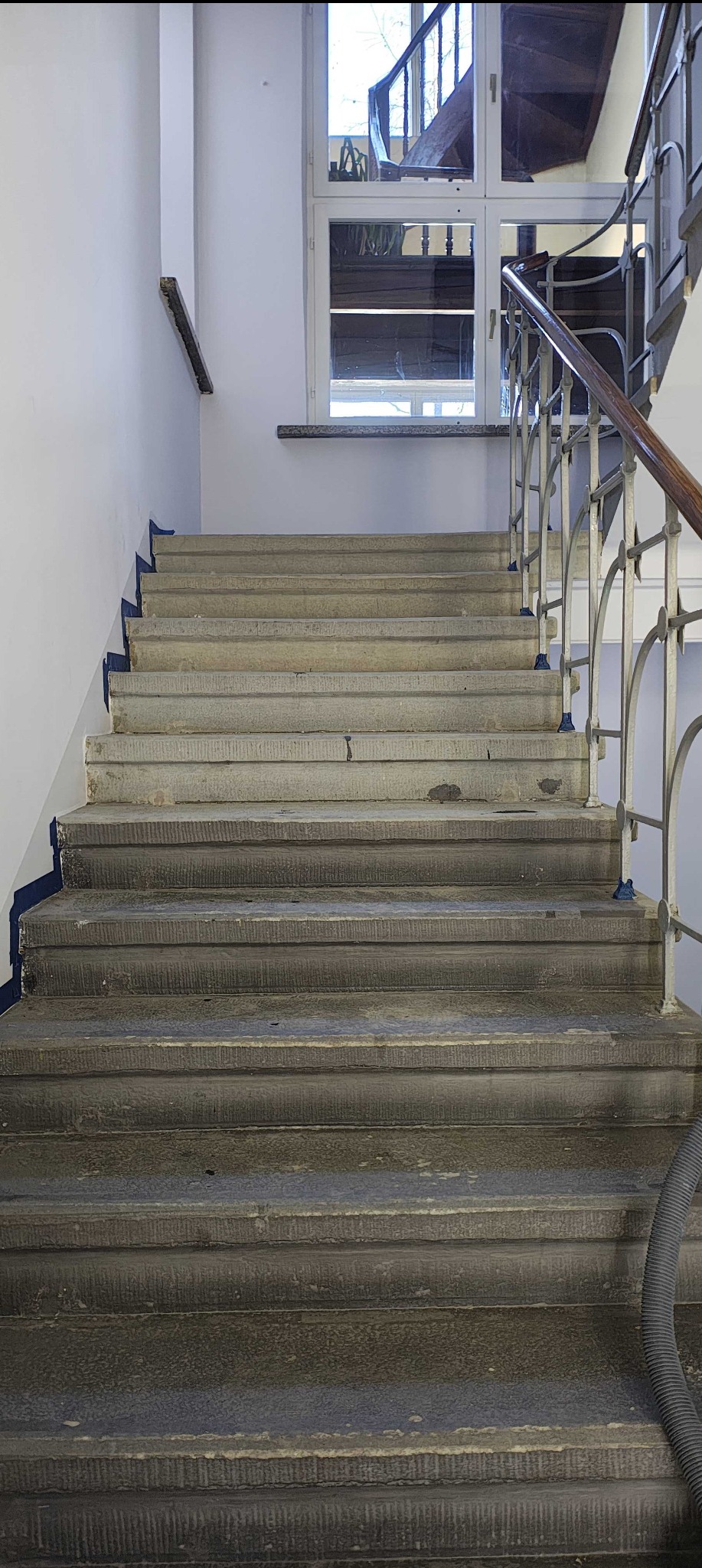 Schody z piaskowca częściowo wyczyszczone z brudu i powłok zabezpieczających.