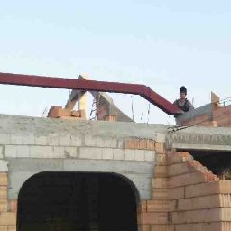 Jan-weld Usługi spawalnicze - Wznoszenie konstrukcji z cegieł i betonu; widoczna stalowa belka stropowa i pracownik w odzieży roboczej na tle nieba.