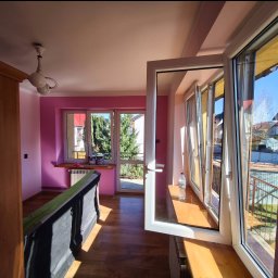 MULTI-FINISH - Pokój po odświeżeniu z różowymi ścianami, otwartym oknem balkonowym i widocznymi puszkami farb na parapecie.