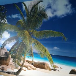 MULTI-FINISH - Fototapeta na ścianie przedstawiająca tropikalną plażę z palmą, błękitnym niebem i białym piaskiem, częściowo zasłonięta przez meble.