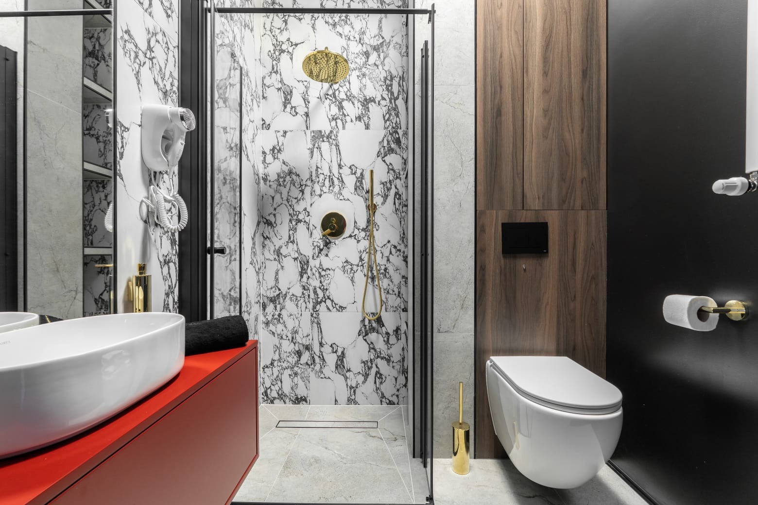 Nowoczesna łazienka z kabiną prysznicową typu walk-in, marmurowymi płytkami, czerwoną szafką pod umywalką i drewnianymi elementami wykończenia.