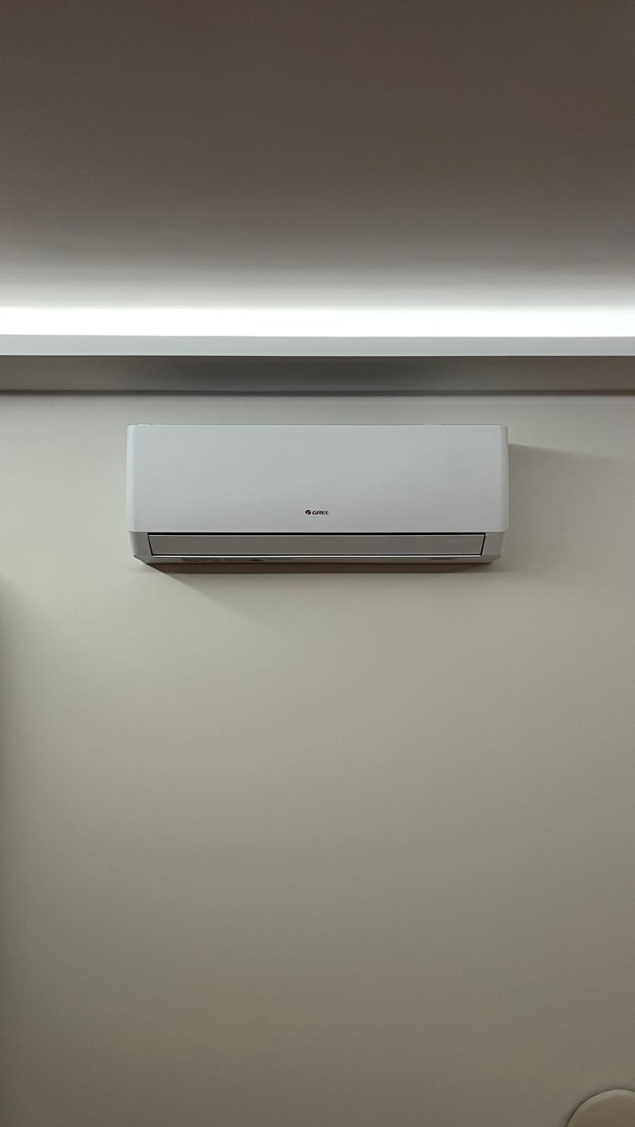 Zamontowany klimatyzator marki Gree na ścianie w jasnym pomieszczeniu we Wrocławiu. Widoczne oświetlenie sufitowe LED. Minimalistyczny design.