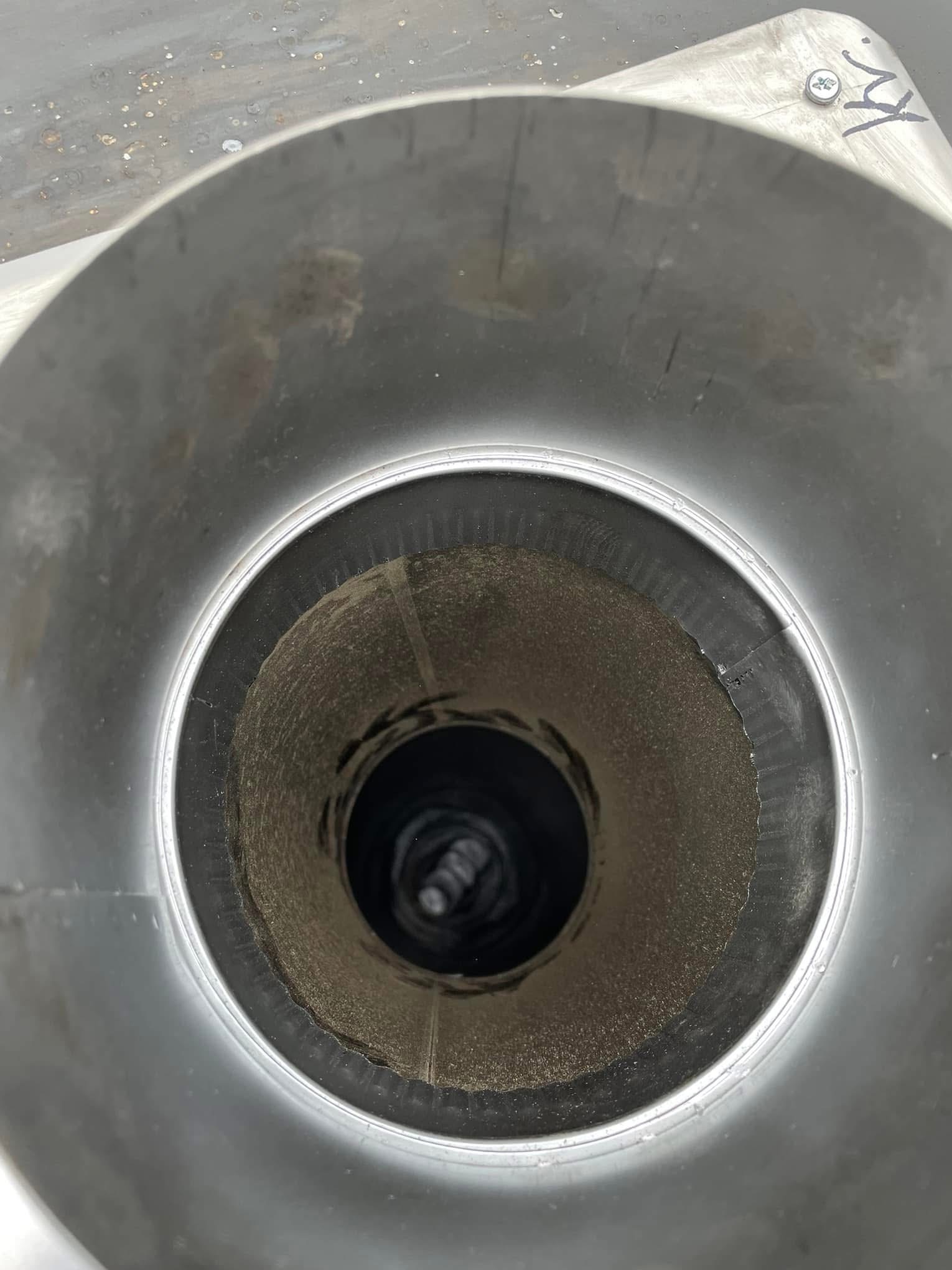 Wnętrze metalowego przewodu wentylacyjnego z widocznymi zabrudzeniami i osadami, sfotografowane od wewnątrz.