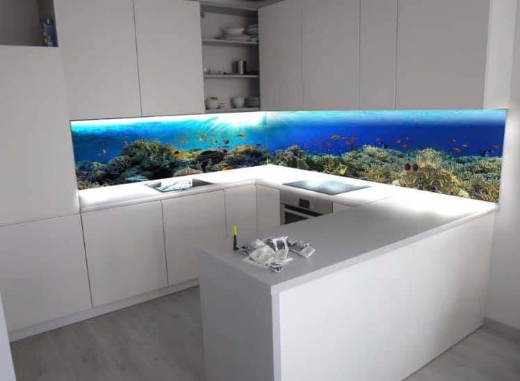 Biała kuchnia z panelem ściennym z motywem podwodnego świata, koralowce i ryby. Nowoczesny design, jasne oświetlenie, minimalistyczny styl.