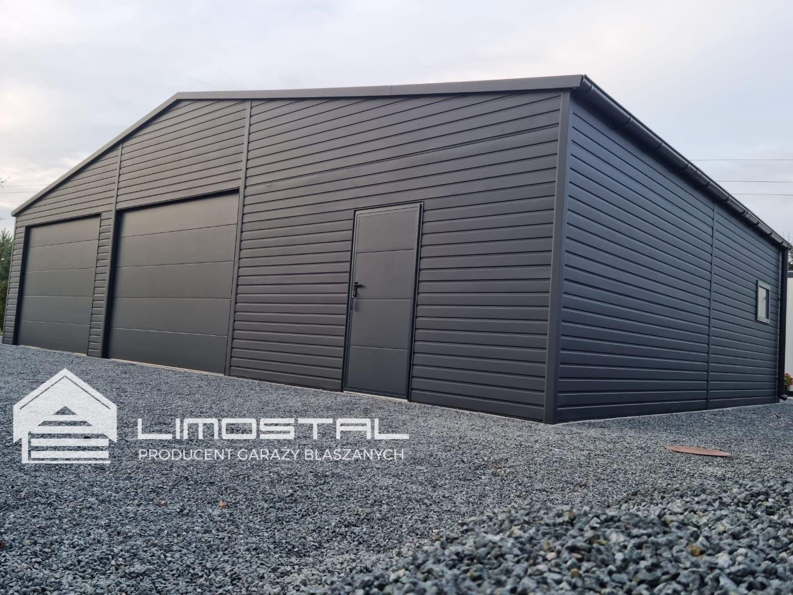 Nowoczesny, grafitowy garaż z dwiema bramami segmentowymi i drzwiami wejściowymi, wykończony poziomymi panelami, na żwirowym podłożu, z logo producenta widocznym na pierwszym planie.
