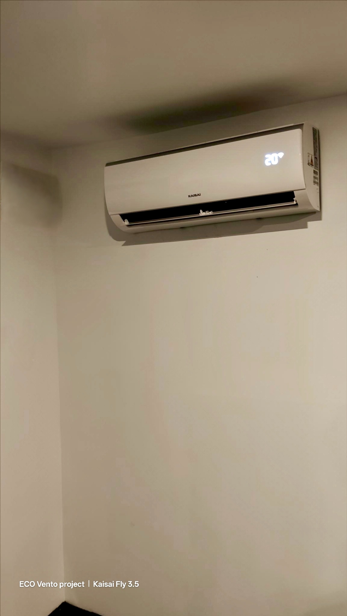 Biała klimatyzacja Kaisai Fly 3.5 zamontowana na ścianie, ustawiona na 20 stopni. Widok z dołu na urządzenie w pomieszczeniu o jasnych ścianach.