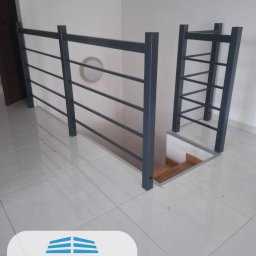 OWBET Bramy i Ogrodzenia - Szara, metalowa balustrada schodowa z poziomymi prętami i drabinką na antresoli, widok z góry na białe płytki podłogowe.