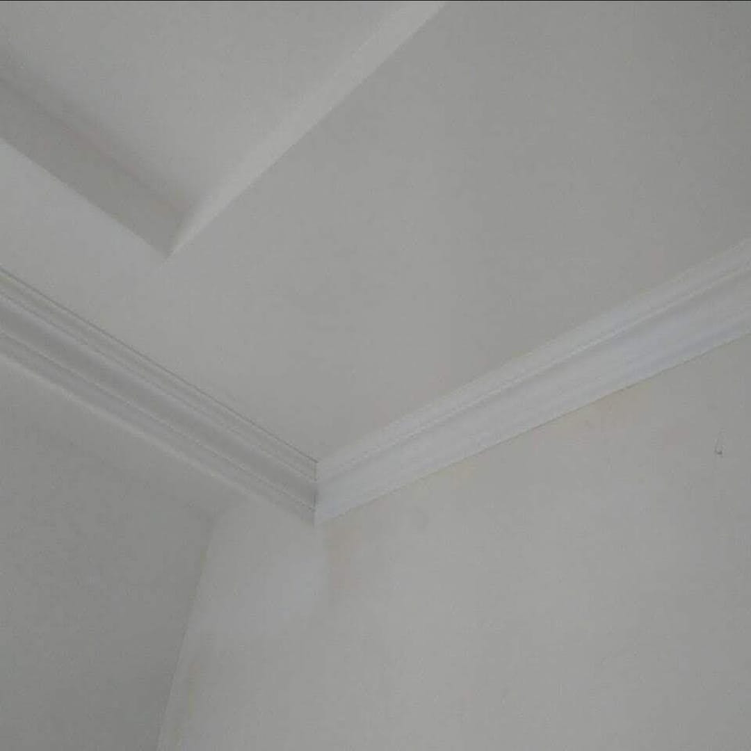 Białe listwy dekoracyjne zamontowane na styku ściany i sufitu, widoczne pod kątem.