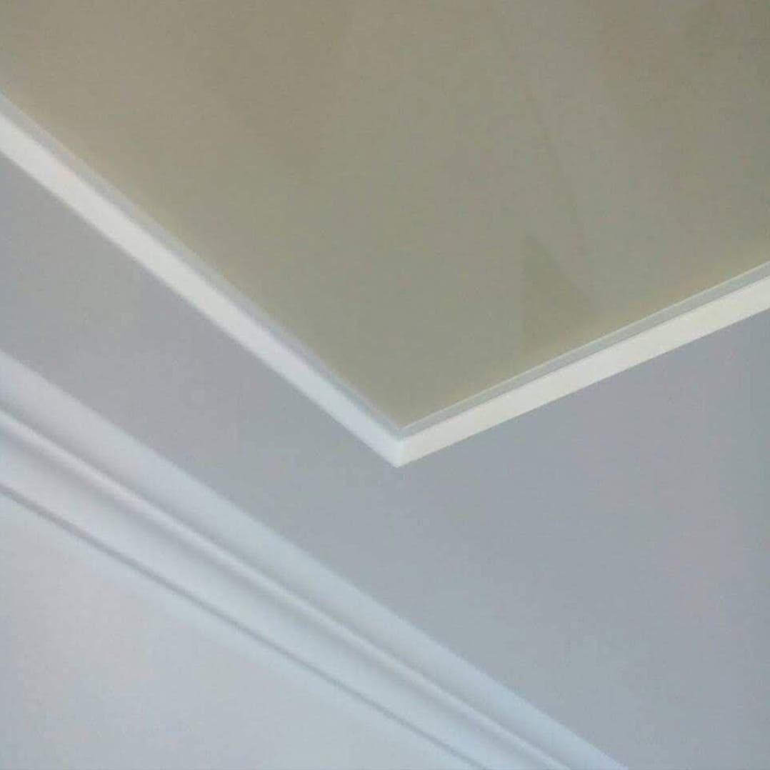 Fragment sufitu z dekoracyjną listwą przysufitową i podwieszanym sufitem z połyskiem, widocznym pod kątem.