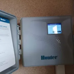 Otwarty panel sterowania nawadnianiem Hunter PRO-HC Wi-Fi z komunikatem o błędzie połączenia bezprzewodowego, instrukcja obsługi wewnątrz pokrywy.