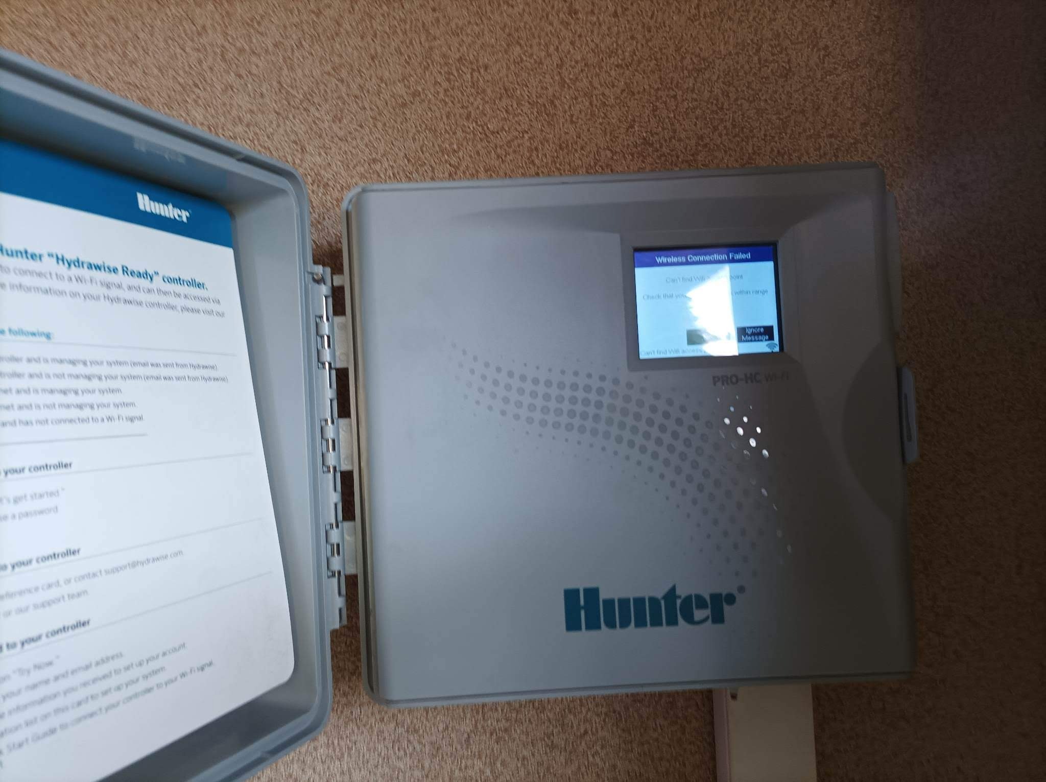 Otwarty panel sterowania nawadnianiem Hunter PRO-HC Wi-Fi z komunikatem o błędzie połączenia bezprzewodowego, instrukcja obsługi wewnątrz pokrywy.