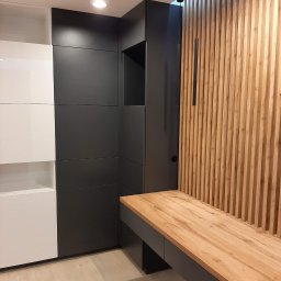 Da Vinci Sztuka Mebli - Nowoczesna zabudowa przedpokoju z szafą w kolorach bieli i antracytu, uzupełniona drewnianym panelem lamelowym i blatem z naturalnego drewna.