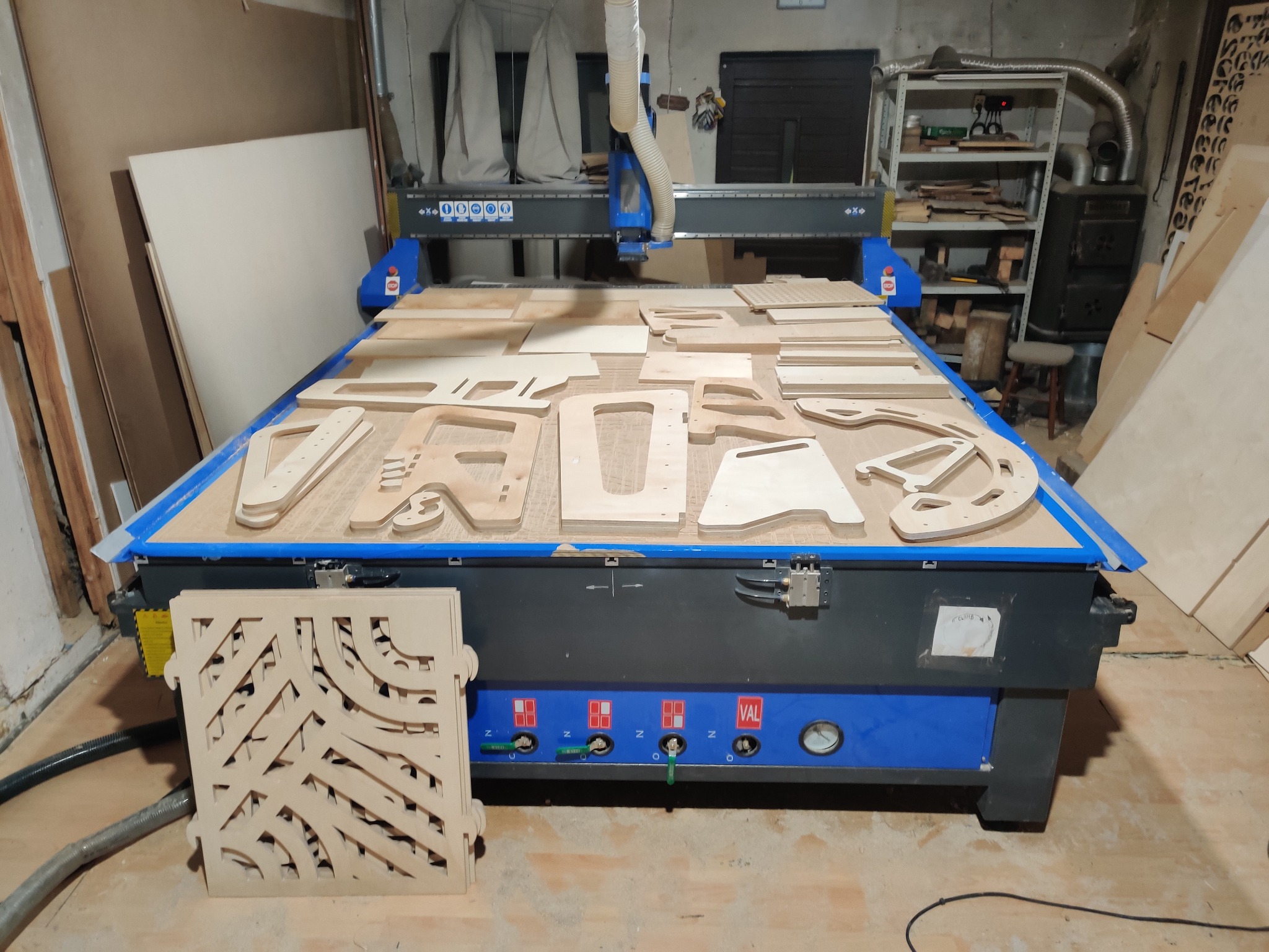 Frezarka CNC z elementami wyciętymi z jasnej sklejki, widoczny panel sterowania i detale wykończeniowe