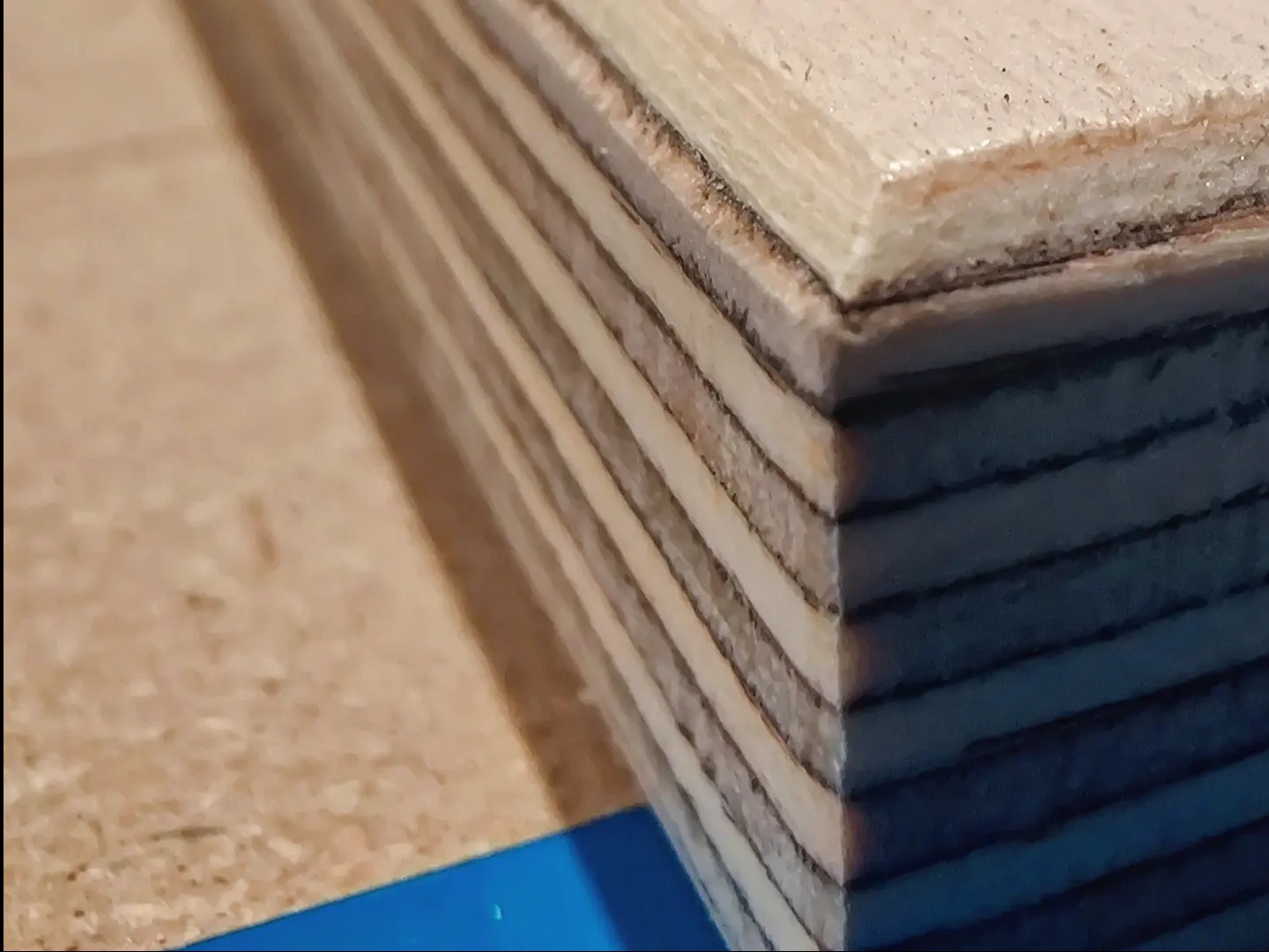 Przekrój warstw sklejki z widocznymi słojami drewna, ujęcie makro ukazujące strukturę materiału.