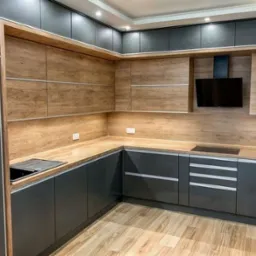 Nowoczesna kuchnia z szarymi szafkami na wysoki połysk i drewnianymi frontami górnych szafek, drewniany blat, płyta indukcyjna i czarny okap.