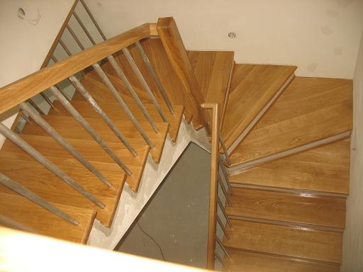 Drewniane schody z metalową balustradą, widok z góry, stopnie o naturalnym odcieniu drewna.