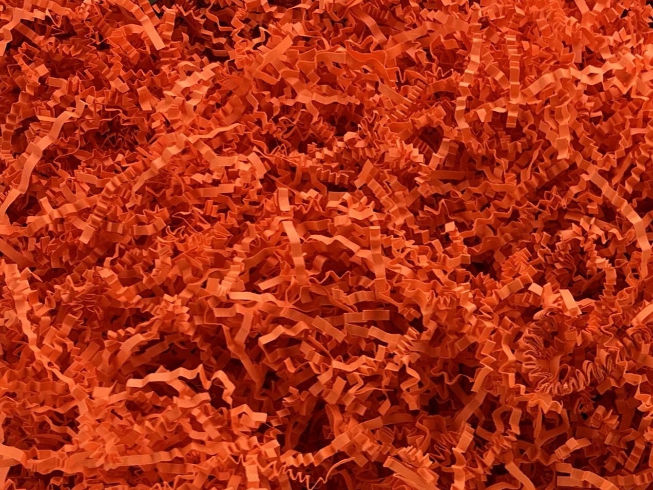 Pomarańczowe, pocięte paski papieru, wypełnienie do paczek, widok z góry.