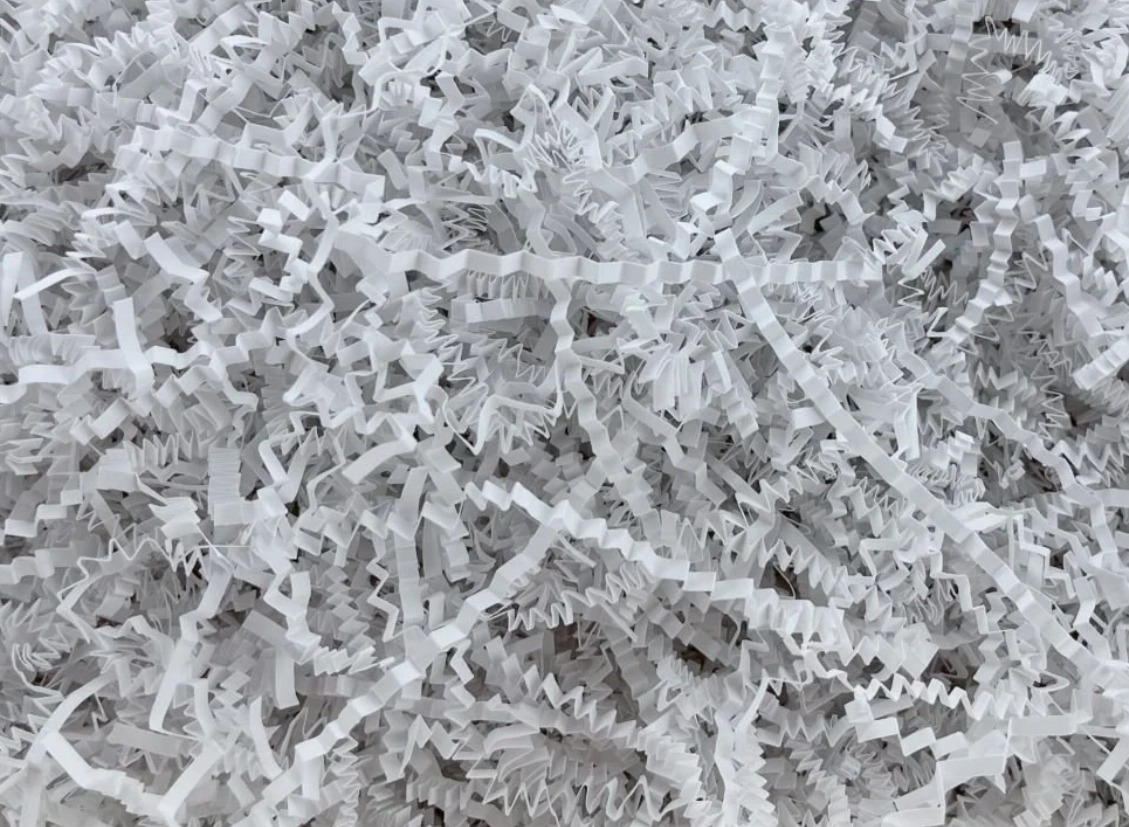 Wypełnienie z białej, pociętej papierowej rafii, idealne do pakowania prezentów i delikatnych przedmiotów, widok z góry.