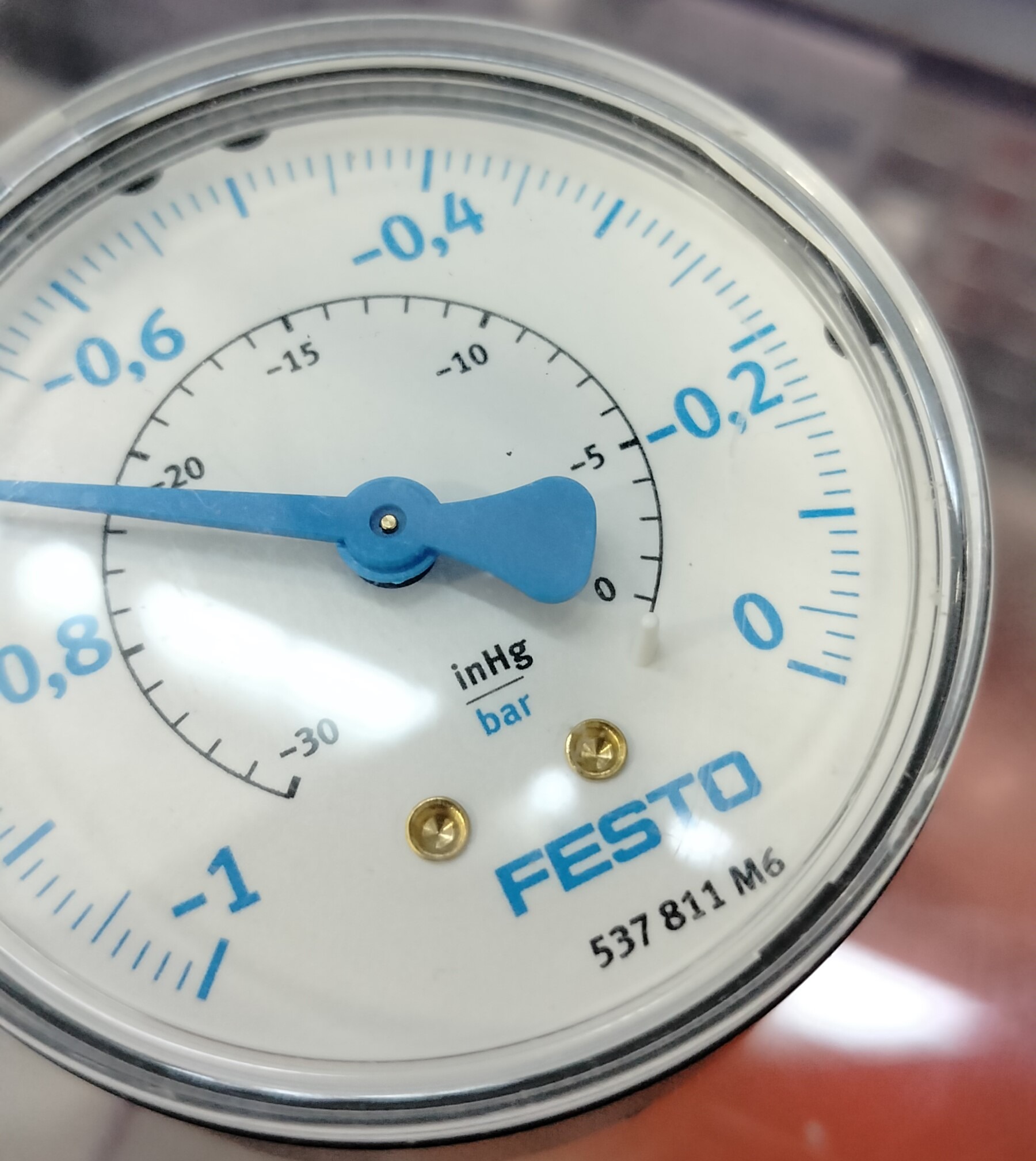 Manometr analogowy marki Festo, wskazujący wartość podciśnienia, z niebieską wskazówką ustawioną na około -0.7 inHg.