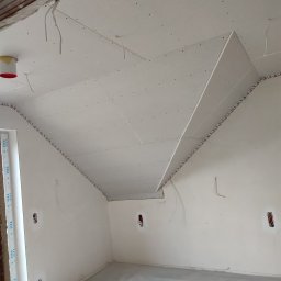 M&D BUD - Montaż sufitu podwieszanego z płyt gipsowo-kartonowych w pokoju, widoczne profile przy ścianach i wystające przewody elektryczne.