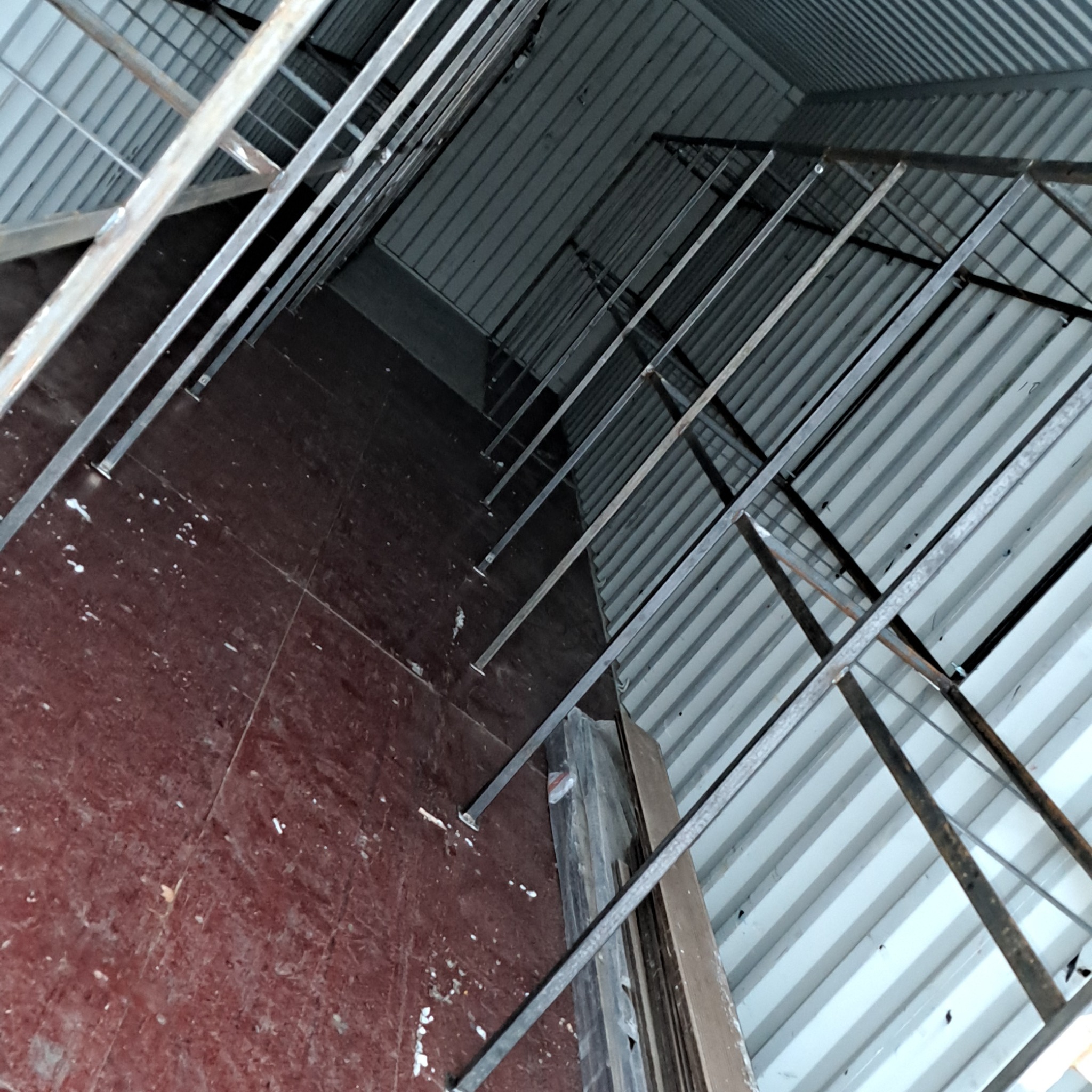 Wnętrze hali w budowie z widoczną konstrukcją stalową dachu i ścian. Elementy konstrukcyjne zespawane, surowy stan wykończenia, widok z dołu pod kątem.