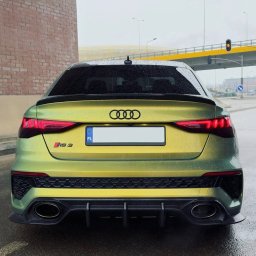 My Clean. Car Premium Detailing - Żółto-zielony Audi RS3 po oklejeniu folią, widok z tyłu na mokrej nawierzchni. Widoczne detale: czarny dyfuzor, logo Audi i oznaczenie modelu.