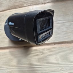 Kranikontakt - Czarna kamera monitoringu Dahua typu bullet, z widocznym obiektywem i podświetleniem IR, zamontowana na jasnej drewnianej elewacji.