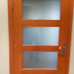 Drewniane drzwi wewnętrzne z trzema szybami matowymi, wykończone w ciepłym odcieniu brązu. Realizacja w Stęszewie. Minimalistyczny design.