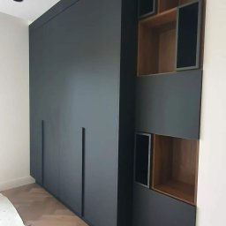 AGNIESZKA WIELGOCKA-PAWLAK NAP studio projektowo-meblarskie - Ciemnoszara szafa na wymiar z minimalistycznymi uchwytami i otwartymi półkami z drewnianym wnętrzem.
