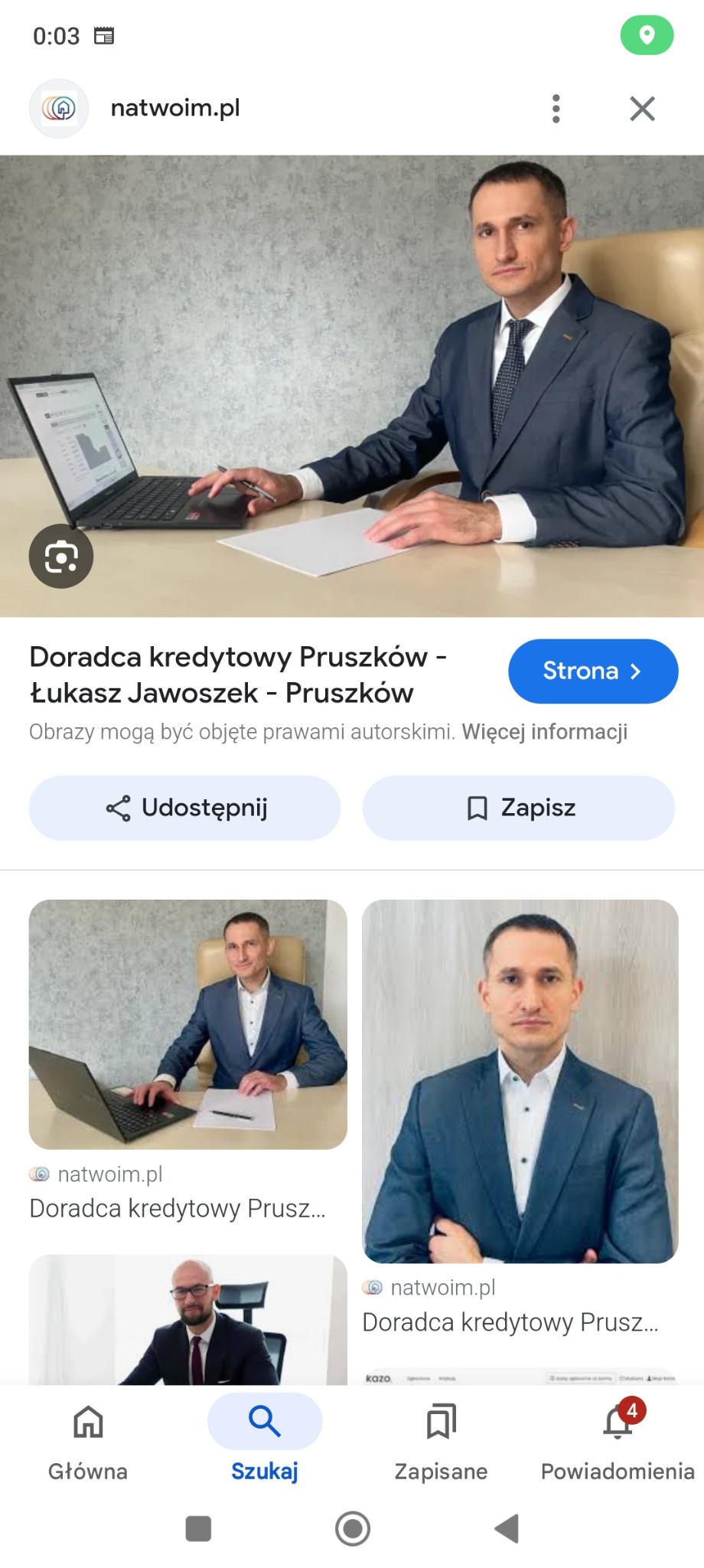 Mężczyzna w garniturze siedzi przy biurku z laptopem i kartką papieru, prezentując dane na ekranie komputera.