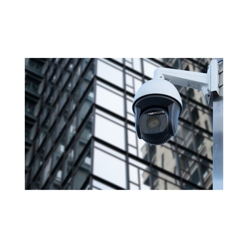 Kamera obrotowa PTZ zamontowana na słupie, z nowoczesnym budynkiem biurowym w tle.