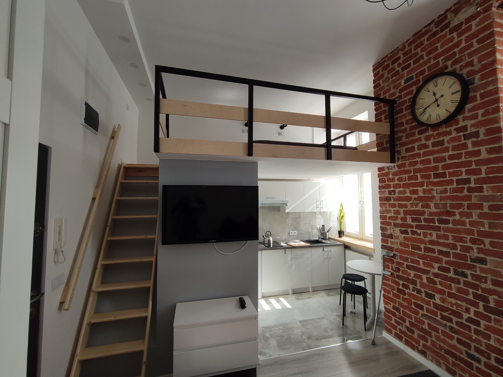 Małe mieszkanie z łazienką pod antresolą i aneksem kuchennym.